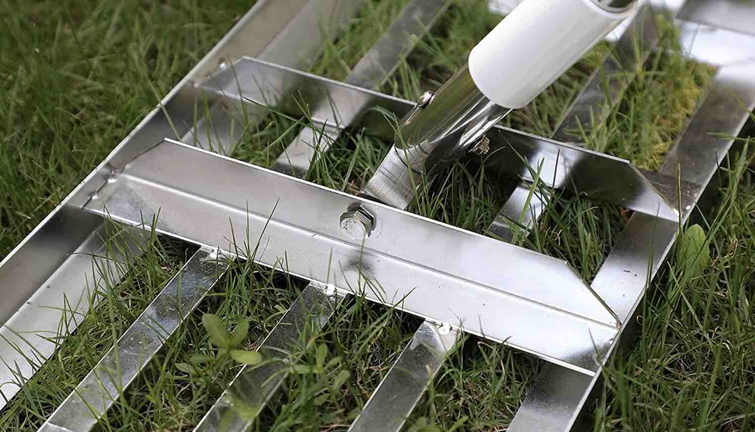 A stainless steel lawn levelling rake resting on freshly cut grass